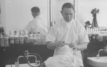 Create a Barbershop experience with a man getting a haircut and enjoying the soothing sensation of a hot towel.