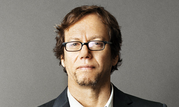 A man in glasses poses for a photo, embodying the Art of Manliness.