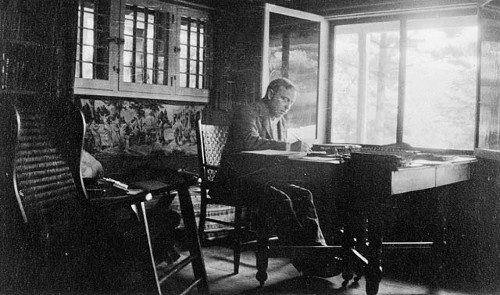 An old photo depicting a man engrossed in his habit of diligently writing in his diary while sitting at a desk.