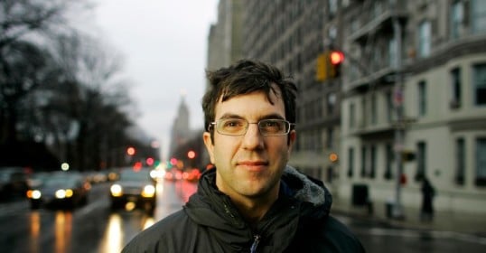 A man in glasses standing on a city street is the epitome of Art of Manliness.