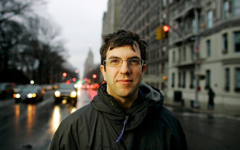 A man in glasses standing on a city street is the epitome of Art of Manliness.