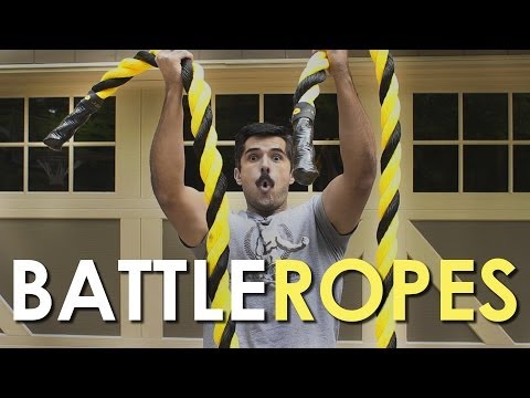 A man is performing Wind Sprints while holding a Battle Rope in front of a garage.