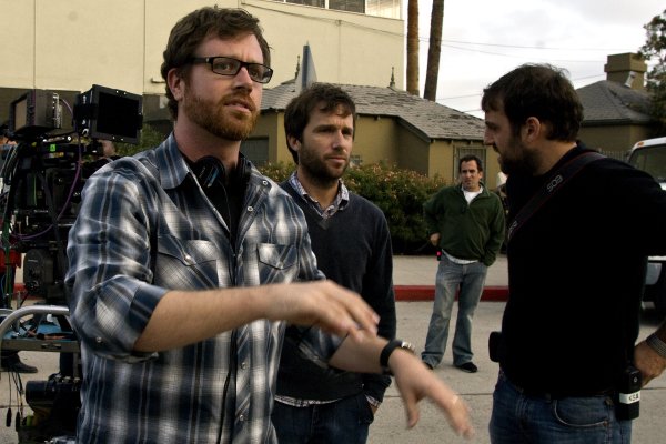 A group of men standing on a street in front of a camera with a film director overlooking the job.