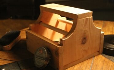 A shoe shine box on a table with a brush and a comb.