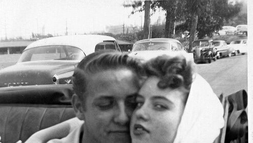 A man and woman dating, hugging in the back of a car.