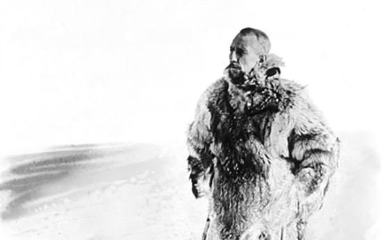 A man in a fur coat standing in the snow on a cold morning.