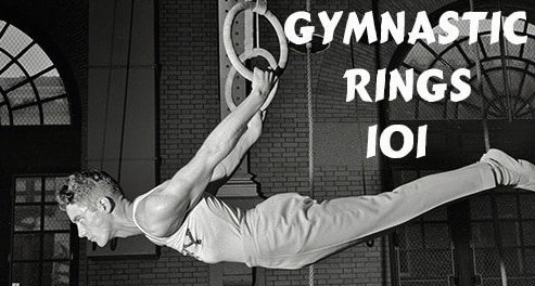 A black and white photo of a gymnast hanging from gymnastic rings.