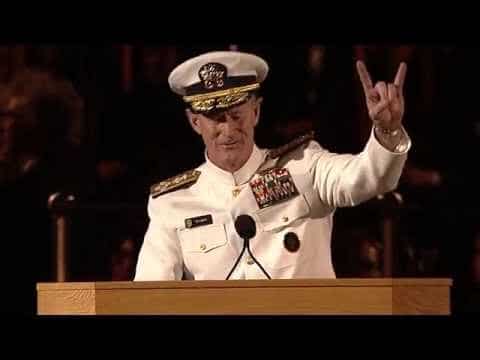 A man in a navy uniform showing peace.