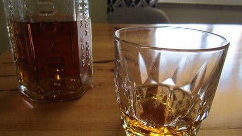 How about a glass of whiskey on a table next to a bottle?