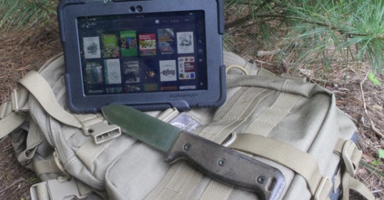 An iPad with a knife sits atop a backpack from the Digital Survival Library.