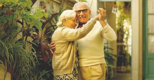 An older couple dancing in a courtyard, showcasing their enduring love.