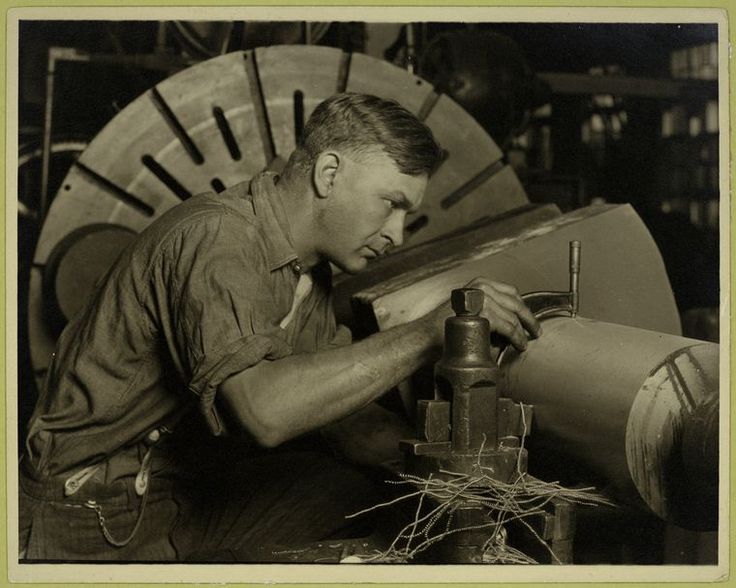 An old photo of a man working on a machine in his blue collar career.
