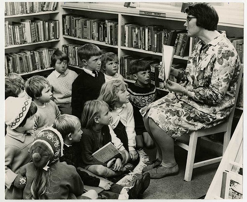 A woman captivates children with a compelling narrative at the library.