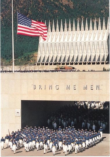 A group of American men standing in front of a building with an American flag.