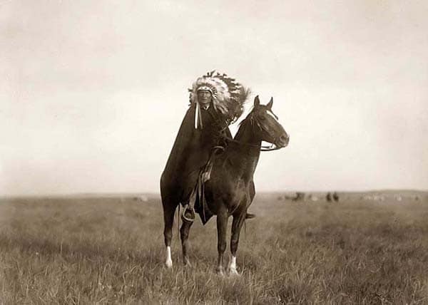 An old photograph of a native american man on horseback.