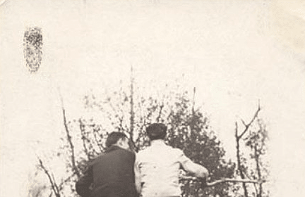 An old photo of two people sitting in a field.