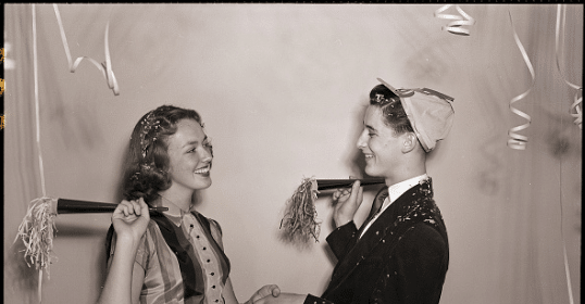 A black and white photo of a couple in a photo booth.