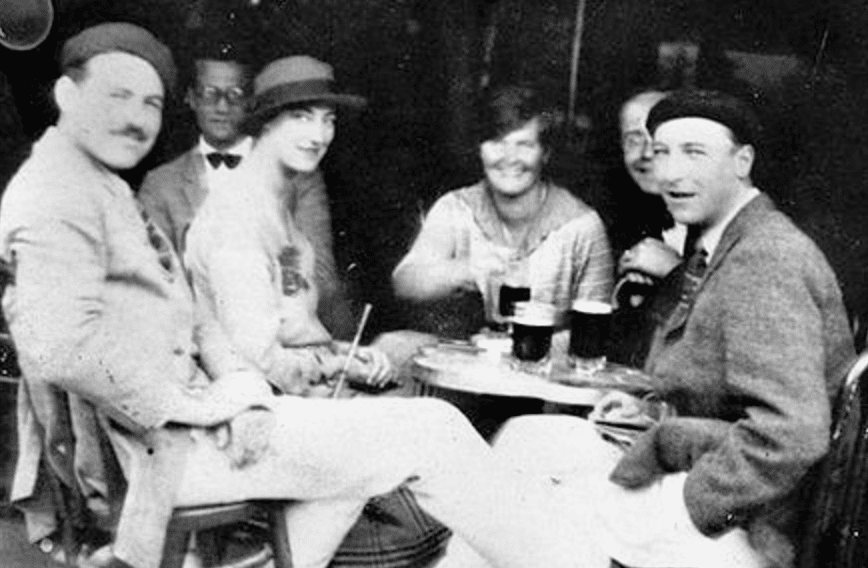 A group of people, reminiscent of a scene from Hemingway's "The Sun Also Rises," sitting around a table.