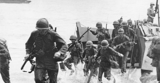 A group of U.S. Marines running through water with determination.