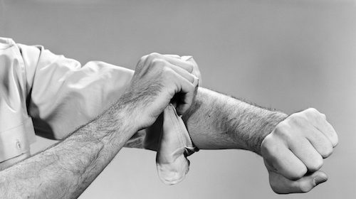 A man in a black and white photo is seen putting a bandage on his arm.