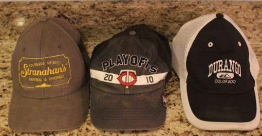 Three clean baseball caps on a counter top.