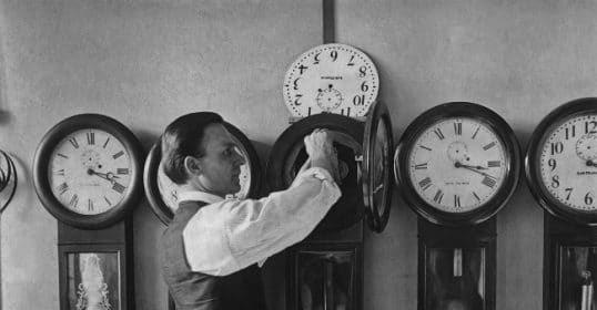 A man is tracking time by putting clocks on a wall.