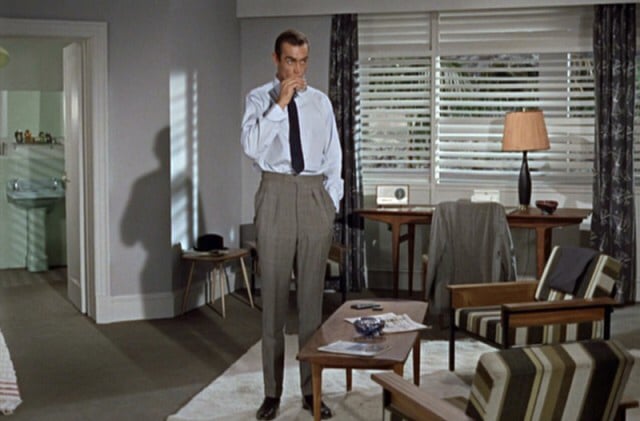 A man in a suit standing in a stylish living room.