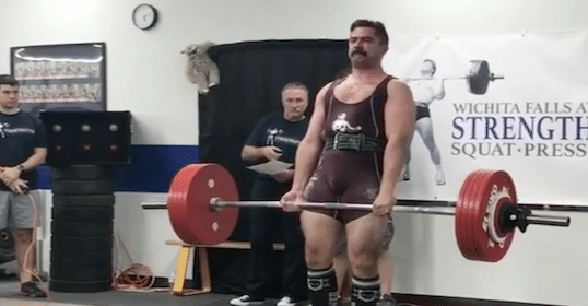 A man lifting a barbell in the gym to gain strength.