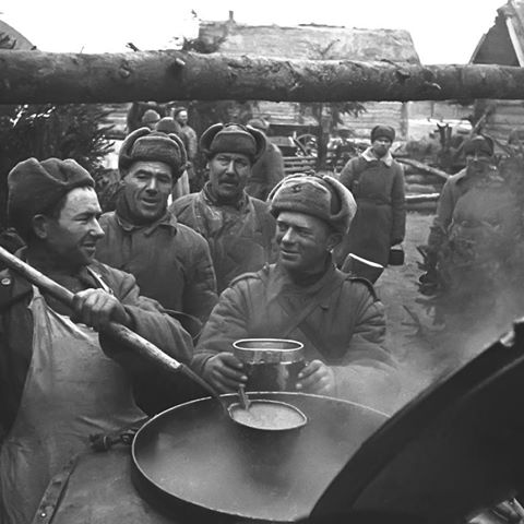 A group of men are cooking food in a pan.