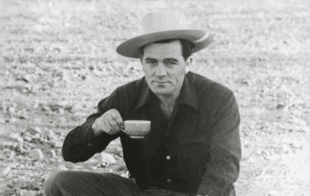 A man in a cowboy hat enjoying a cup of coffee.