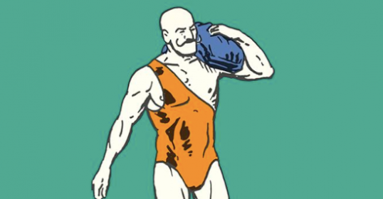 A man in a bathing suit carrying a heavy blue bag.