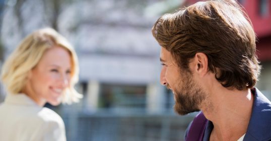 A man and a woman are looking at each other, she knows he likes her.