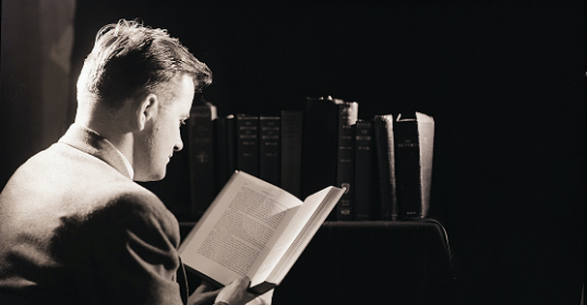 A man in a suit reading more books.