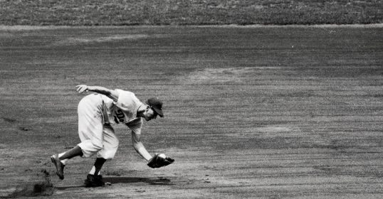 A reactive baseball player catches a ball in this black and white photo.