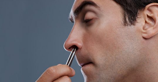 A man is using a brush to clean his nose.