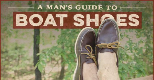 A man's feet in brown boat shoes.