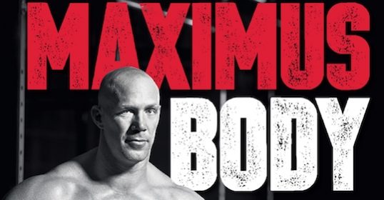 A man in front of a bar showcasing his Maximus body.