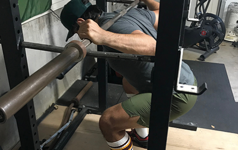 A man doing squats in a gym to treat his tendonitis.