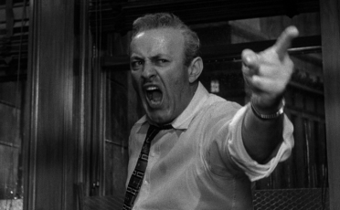 The man is pointing angrily at the door.