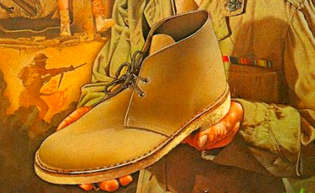 A man is holding a pair of Chukka boots.