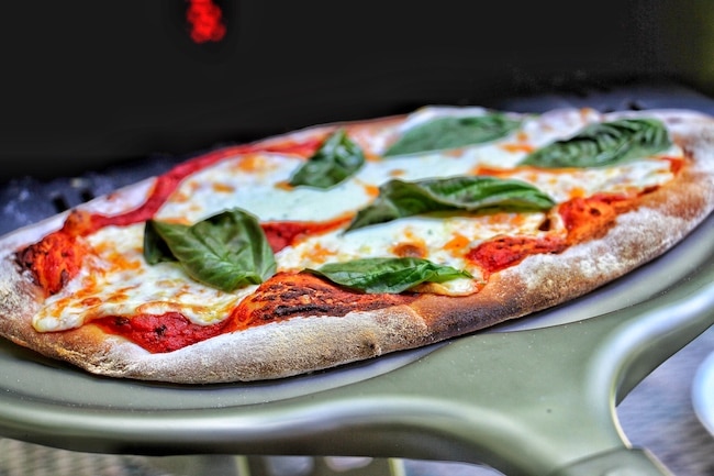 A pizza sitting on top of a grill, making it perfect for restaurant-quality pizza.