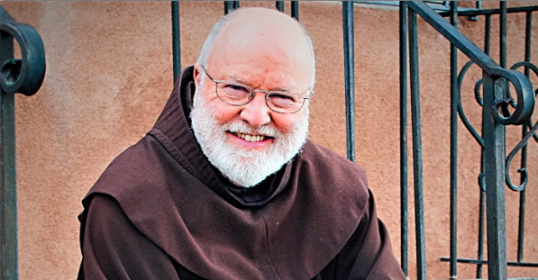 A man in a brown robe sitting on steps, pondering his journey.