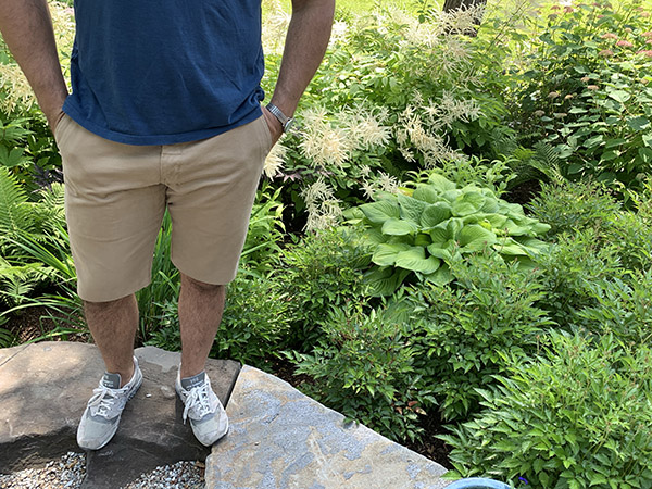 A man standing on a rock in a garden with no pants.