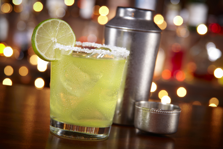 Make the perfect lime margarita on a wooden table.