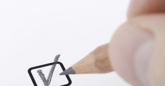 A person is drawing a check mark with a pencil while listening to a Podcast.