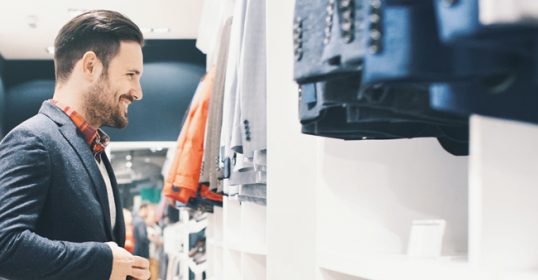 A man browsing through t-shirts and jeans in a clothing store, searching for his perfect style.