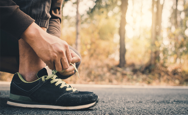 A man tying his shoes on the road, becoming a better man.