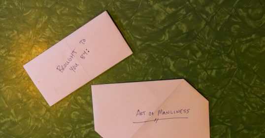 Two folded envelopes with writing on them lay on a green table.