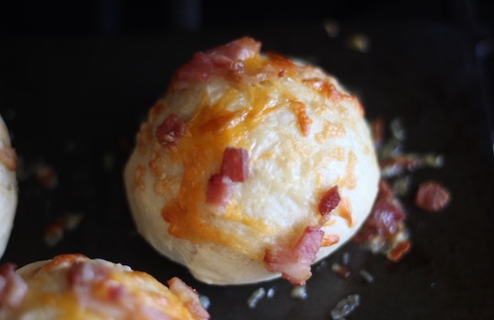 Bacon and cheese rolls on a baking sheet.