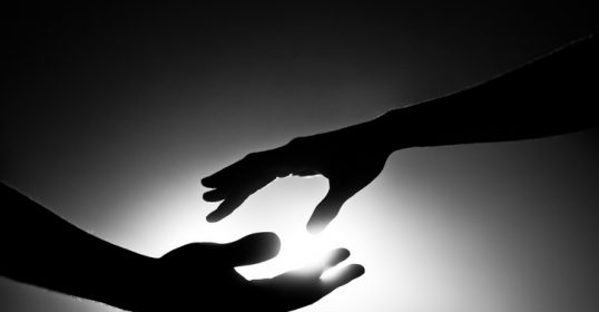 A silhouette of two hands reaching out, symbolizing connection in a lonely world.